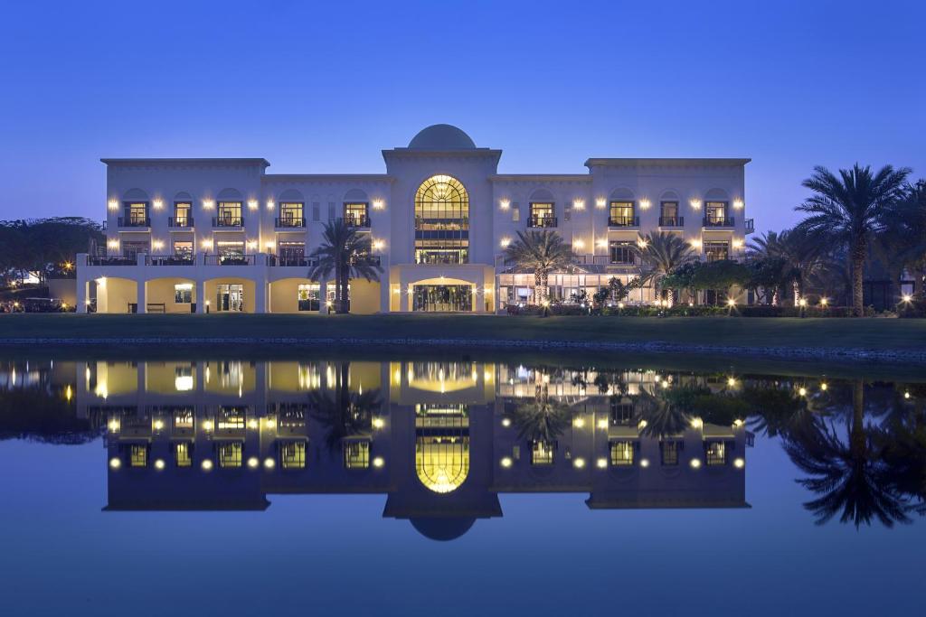 a building with a reflection in the water at night at Address Montgomerie in Dubai