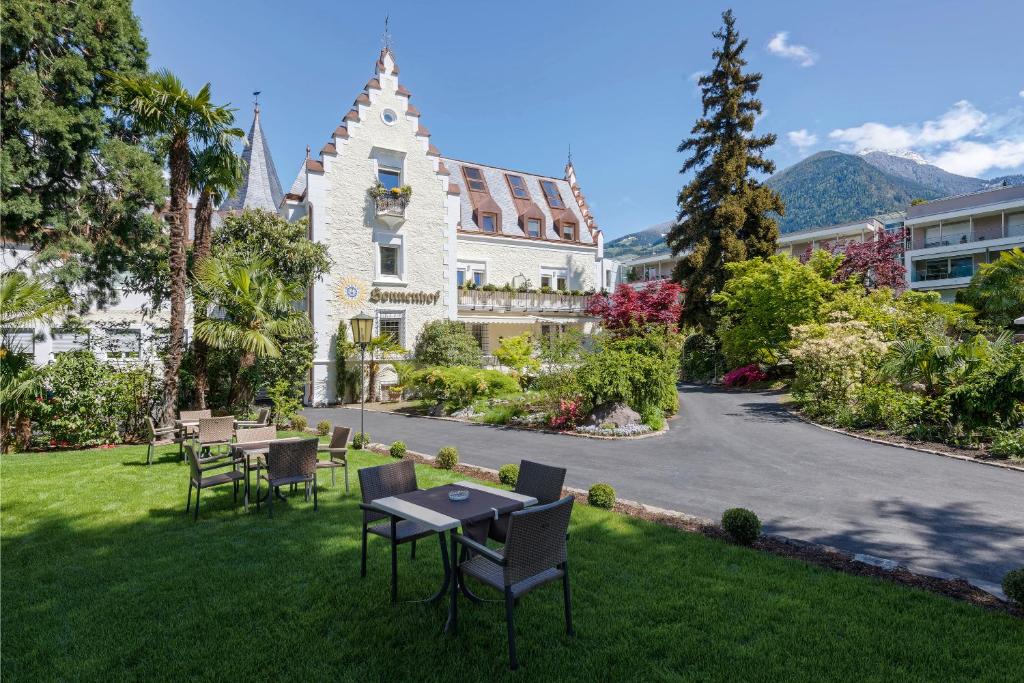 a building with tables and chairs in the grass at Hotel Sonnenhof in Merano