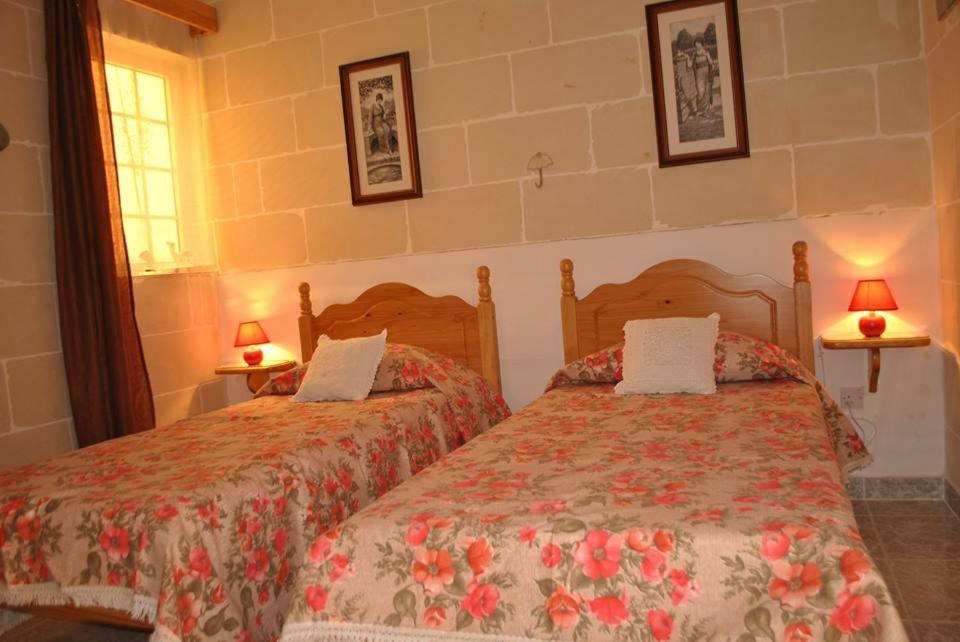 two beds in a bedroom with two lamps on the wall at St Nicholas Crt in Munxar