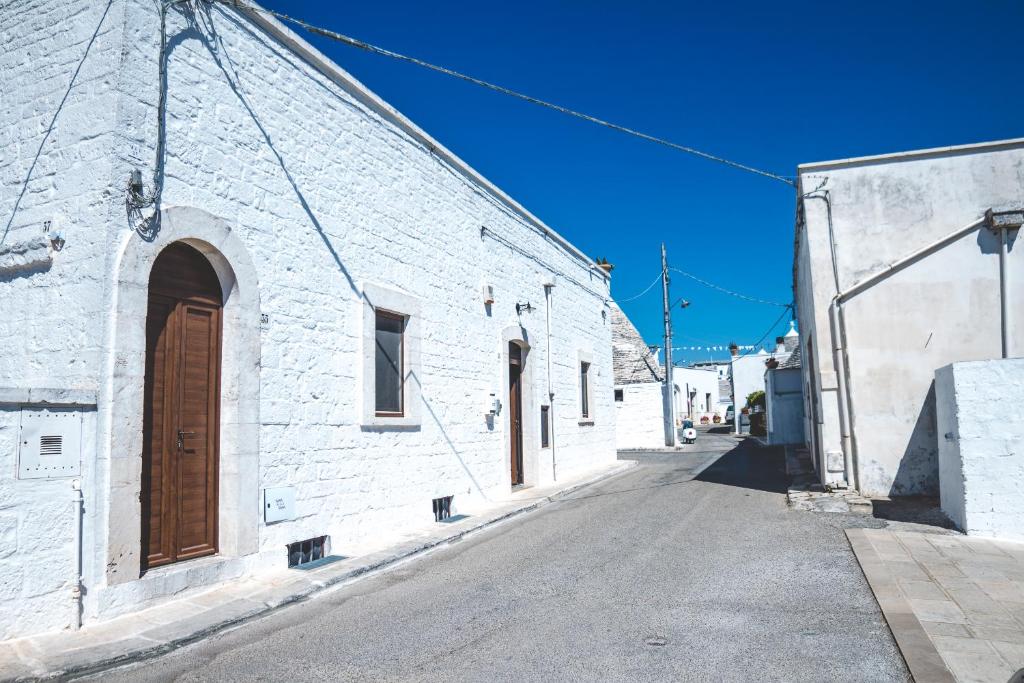 a white brick building with a brown door on a street at Trullieu Guesthouse Alberobello in Alberobello