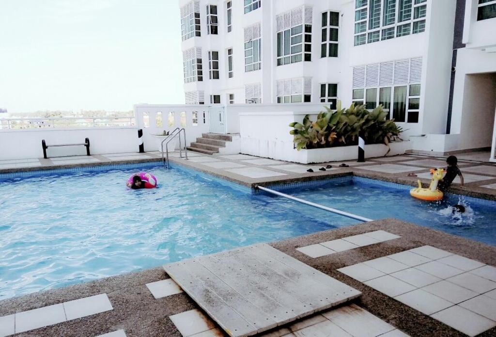 a swimming pool with two children playing in the water at Caliph Suite Apartment Homestay Anjung Vista Kubang Kerian in Kota Bharu