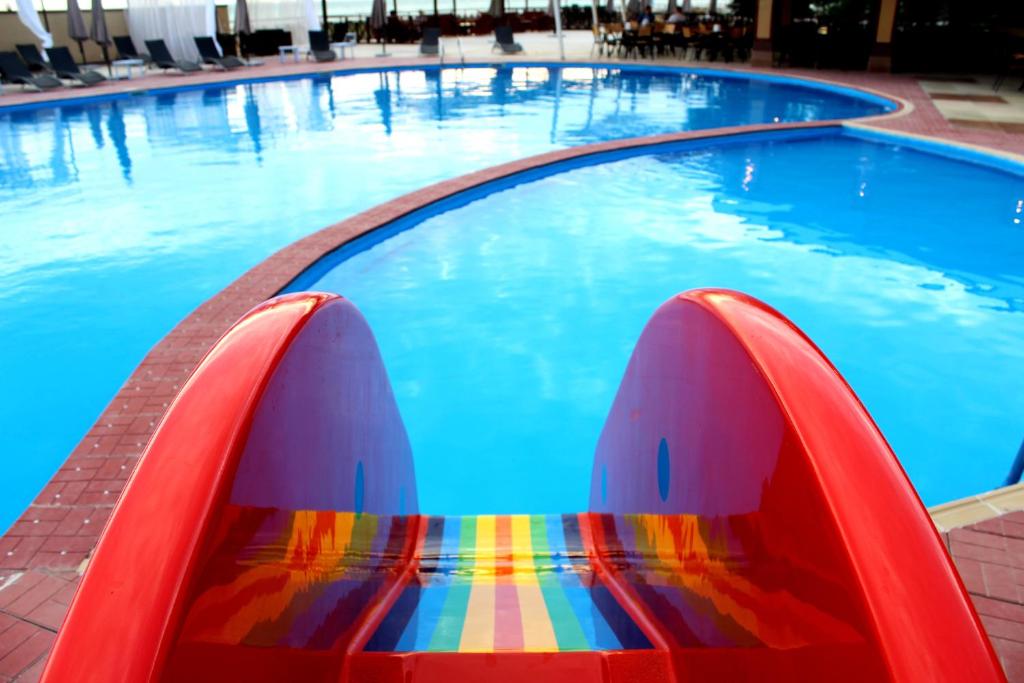 uma piscina com um banco colorido na água em Dostar Hotel em Aktau