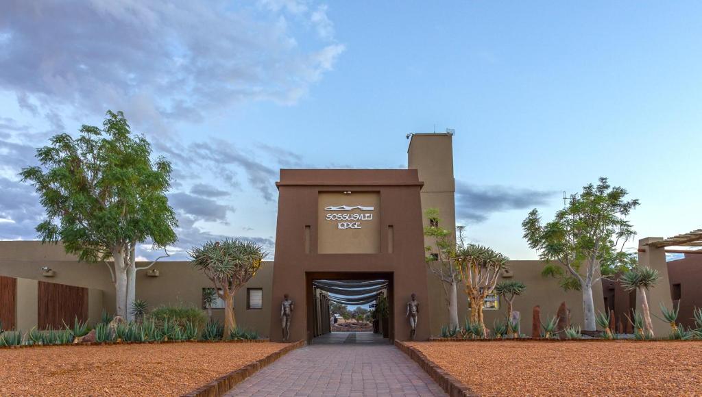 um edifício com um portão em frente com árvores em Sossusvlei Lodge em Sesriem