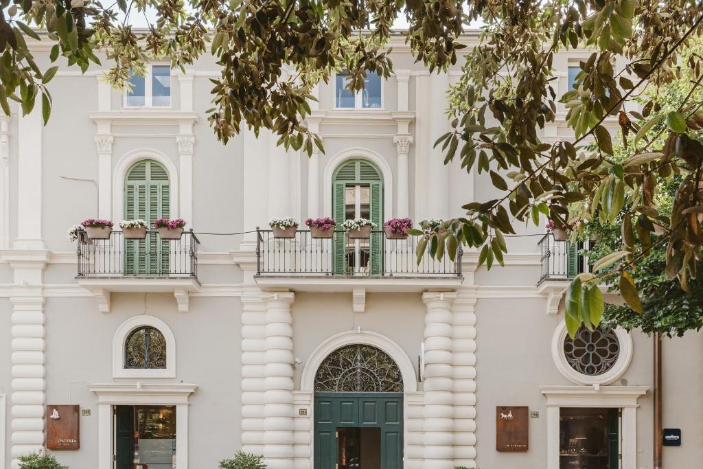 un edificio bianco con porte verdi e fiori sui balconi di La Residenza del Monaco bianco a Matera