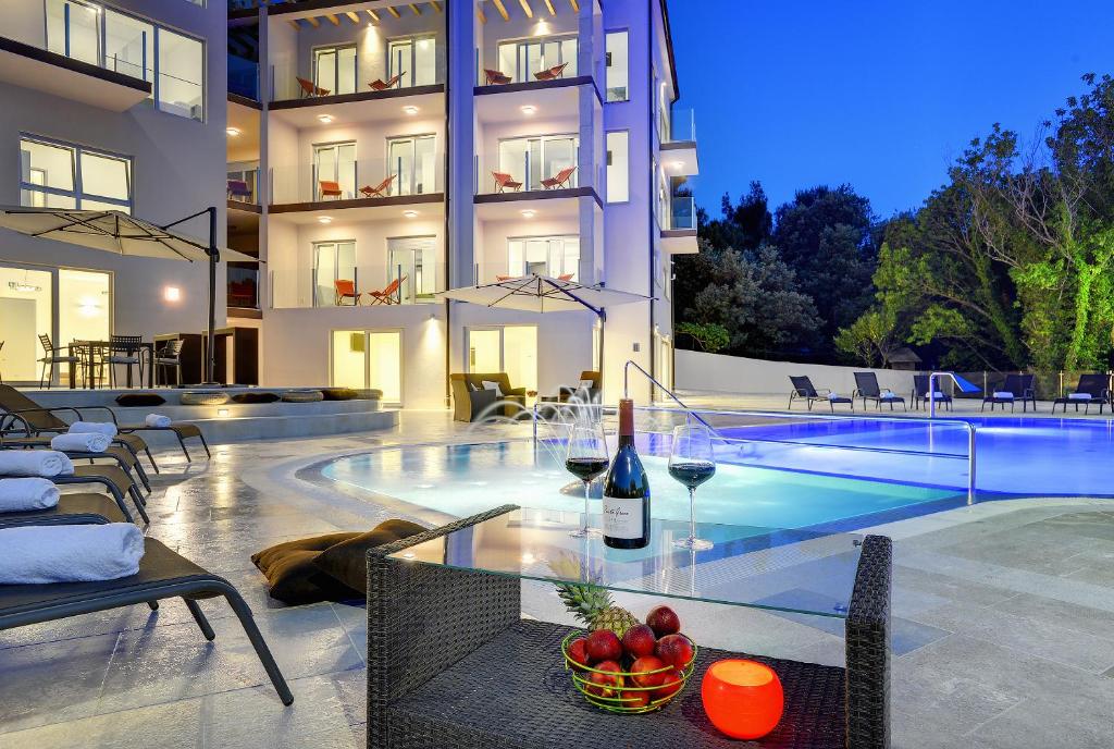 a house with a pool and a table with wine glasses at Premantura Resort - Hotel & Restaurant in Premantura
