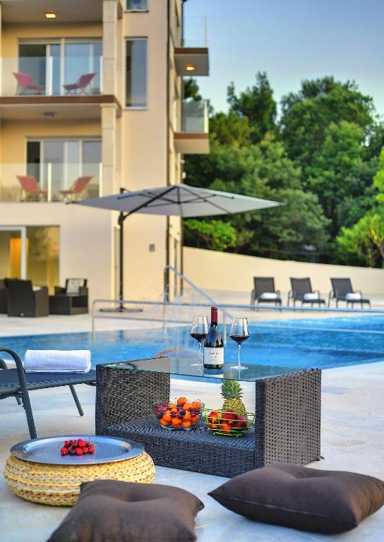 a table with glasses of wine and fruit next to a pool at Premantura Resort - Hotel & Restaurant in Premantura