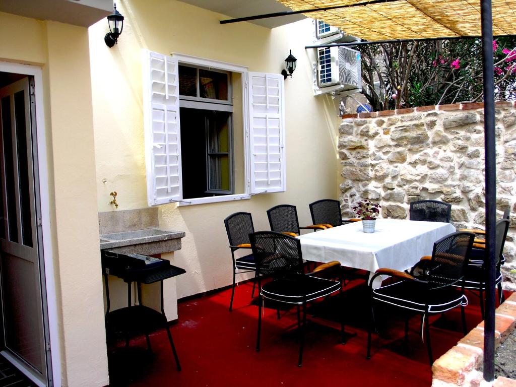 a table and chairs in a patio with a stone wall at Holiday Home Lija Center in Rab