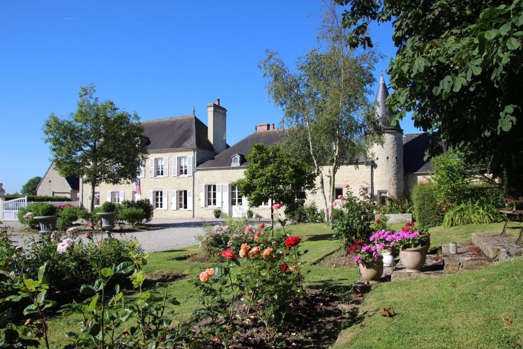uma casa com um jardim com flores em frente em Manoir de Turqueville les Quatre Etoiles em Turqueville