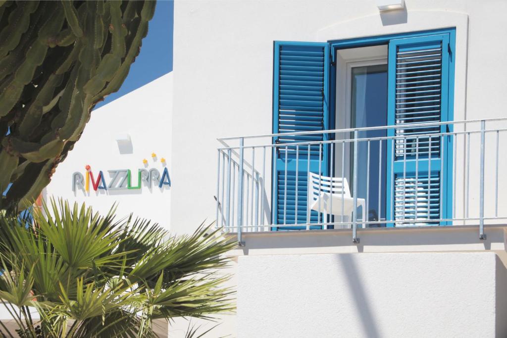 a white house with a blue door and a balcony at Rivazzurra Design Rooms in San Vito lo Capo