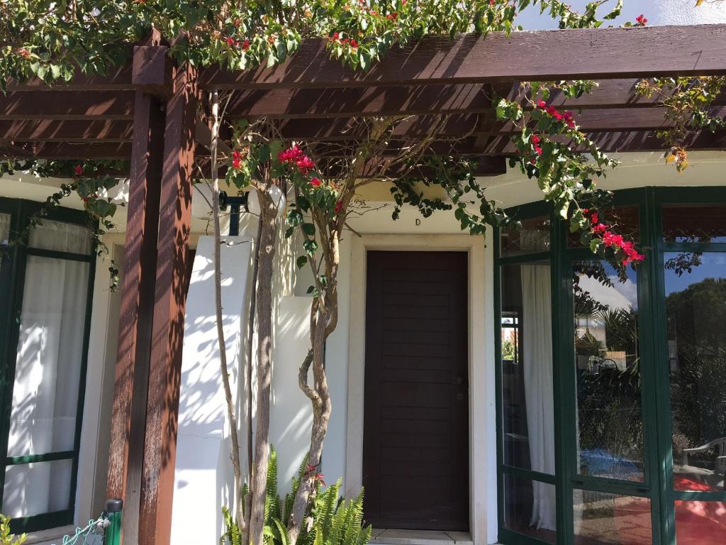 uma pérgola sobre uma porta de uma casa com flores vermelhas em Moradia T3 Soltroia Mar em Troia