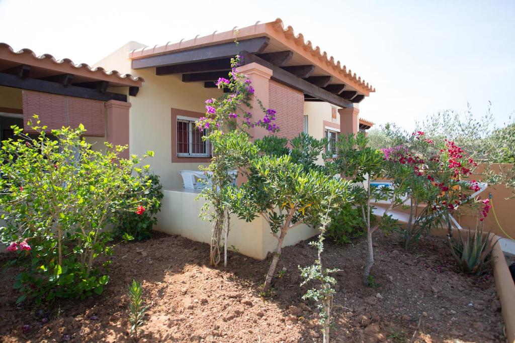 ein Haus mit Bäumen und Blumen davor in der Unterkunft Ca Sa Vilda in Es Pujols