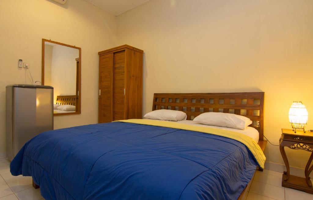 a bedroom with a bed with a blue blanket and a mirror at Pondok Nuri Homestay in Sanur