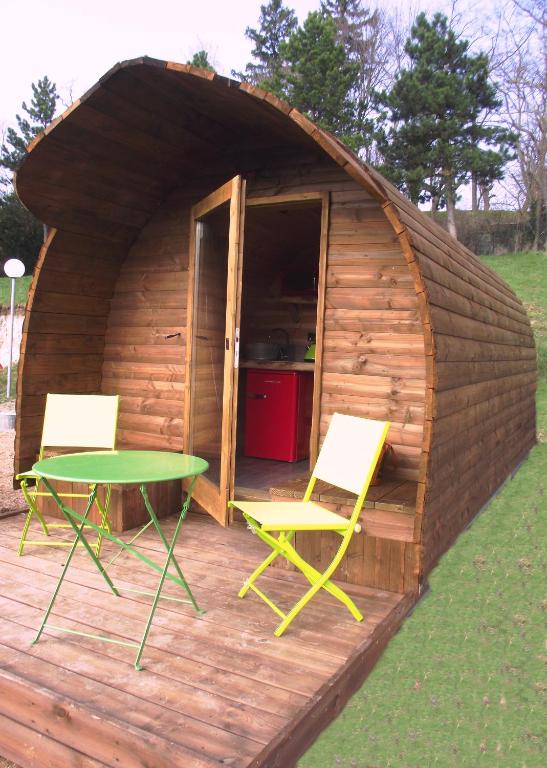 une cabane en bois avec deux chaises et une table en face de celle-ci dans l'établissement La Colline Aux Cabanes, à Espaly-Saint-Marcel