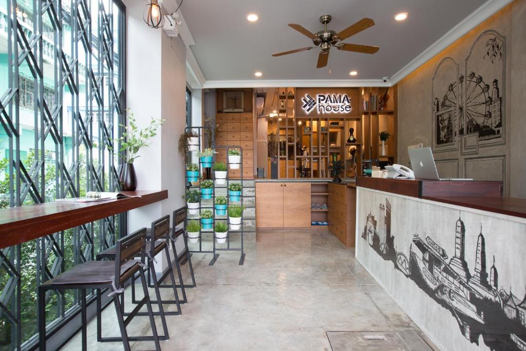 a restaurant with a bar with chairs and windows at PAMAhouse Boutique Hostel in Bangkok