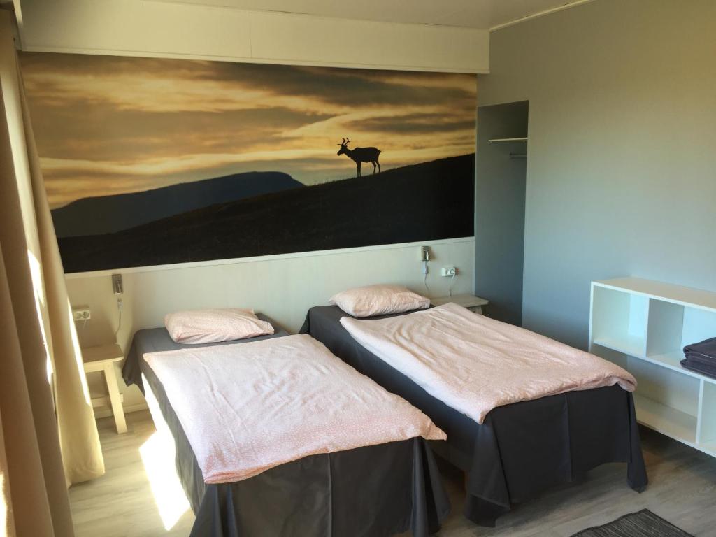 two beds in a room with a painting of a deer on the wall at Guesthouse Borealis in Rovaniemi