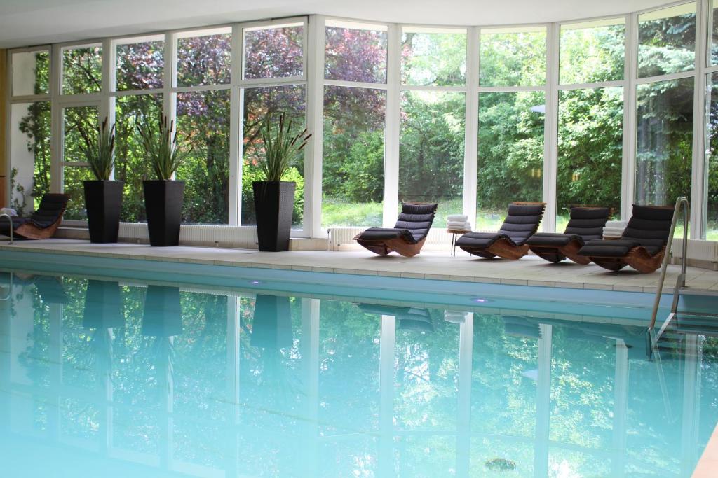 a swimming pool with lounge chairs and windows at Hotel Alexandersbad in Bad Alexandersbad