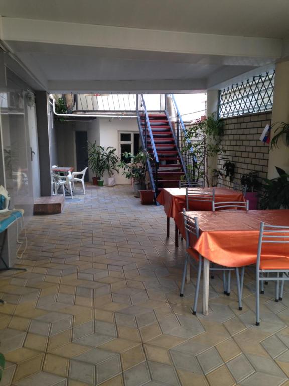 a patio with tables and chairs and a staircase at Guest House Komsomolskiy in Anapa