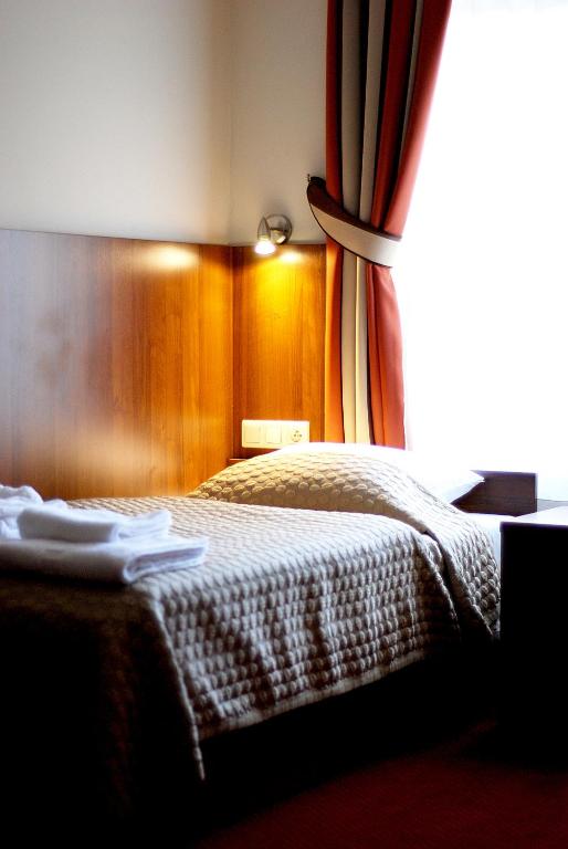 a bedroom with a bed with a curtain and a window at Hotel Alexander in Krakow