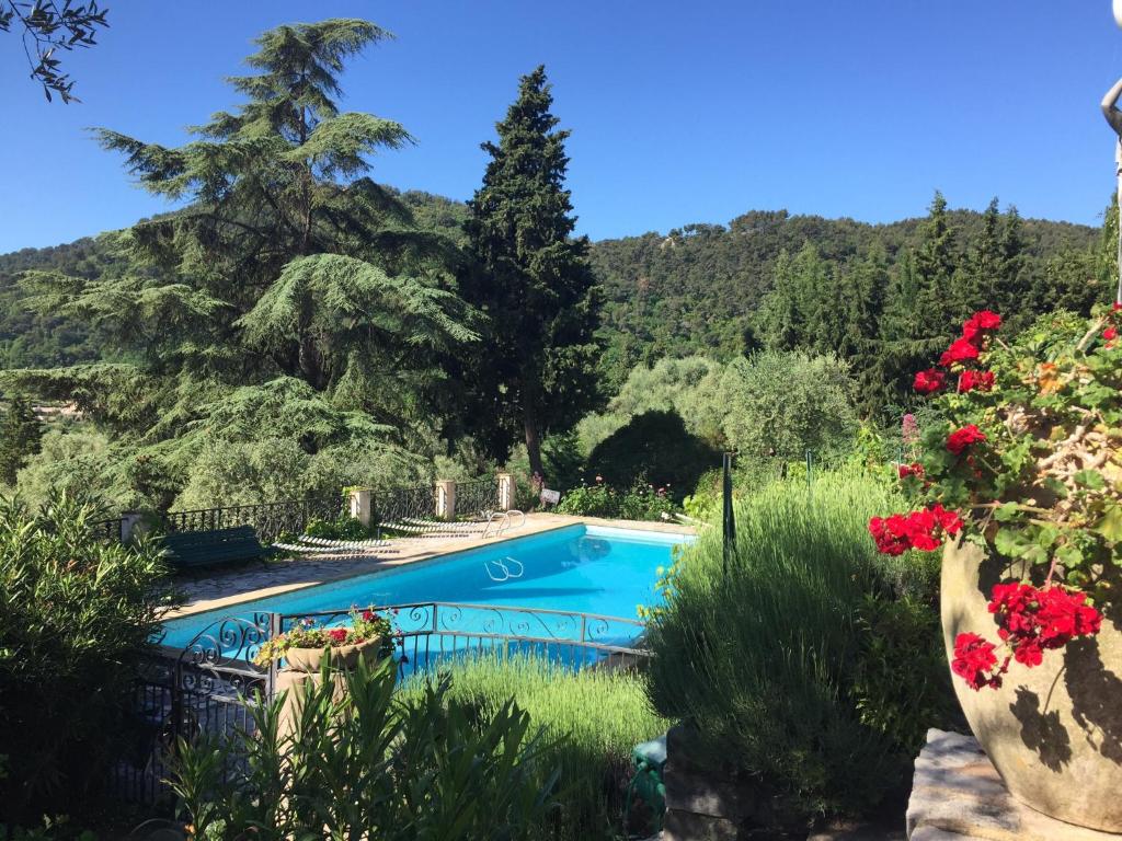 einen Pool in einem Garten mit roten Blumen in der Unterkunft Residence Lou Naouc in Grasse