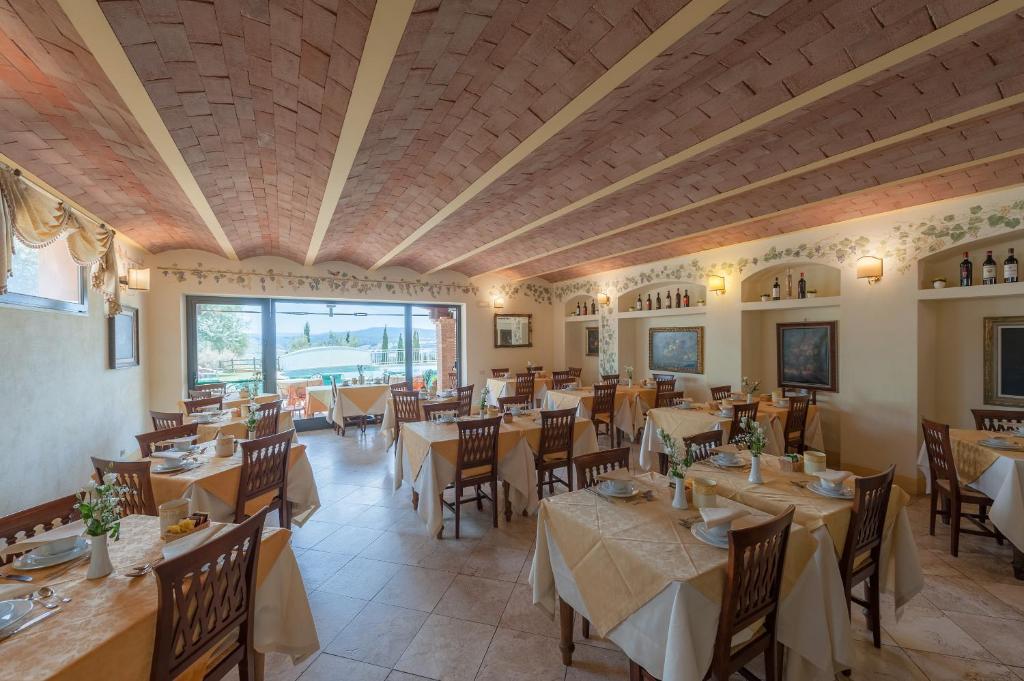 restauracja ze stołami i krzesłami oraz dużym oknem w obiekcie Hotel Saturno Fonte Pura w mieście Saturnia