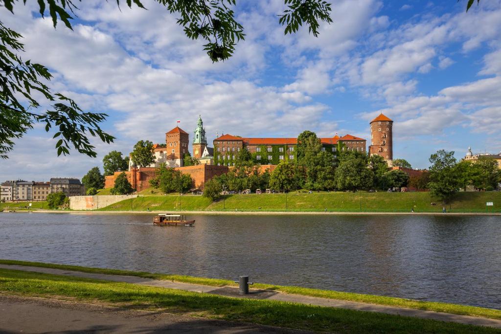 a large building on the shore of a body of water at Friendhouse Apartments Vistula&Wawel in Krakow
