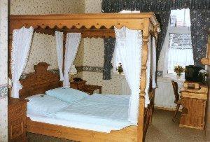 un letto in legno con baldacchino in una camera da letto di Altstadtgasthof Krone a Eschwege