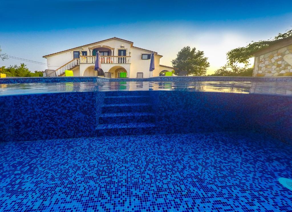 a blue swimming pool with a house in the background at Apartments Chipo in Vodnjan