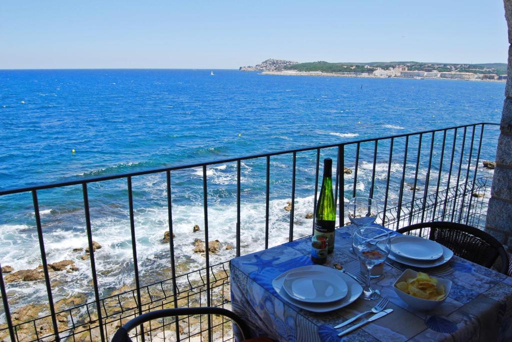 a table with a bottle of wine on a balcony with the ocean at Albatros House in L'Escala
