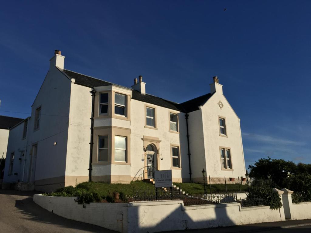 uma casa branca com um telhado preto em The Bowmore House Bed and Breakfast em Bowmore