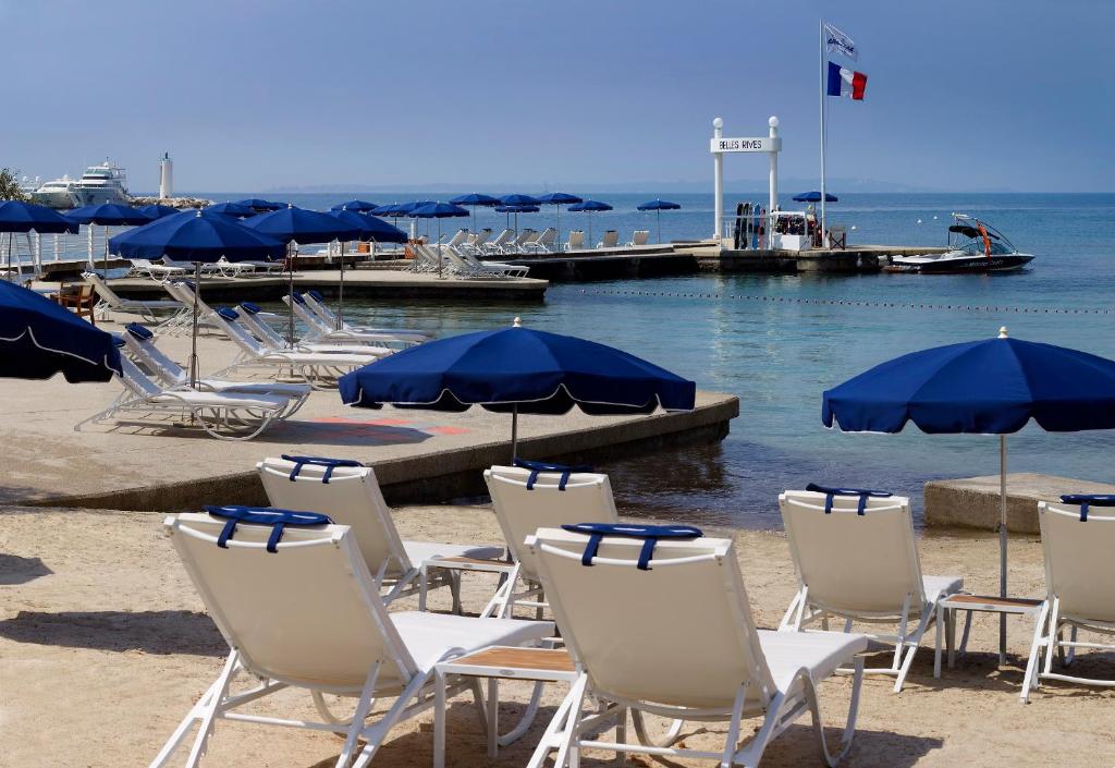 a group of chairs and umbrellas on a beach at Hôtel Belles Rives in Juan-les-Pins