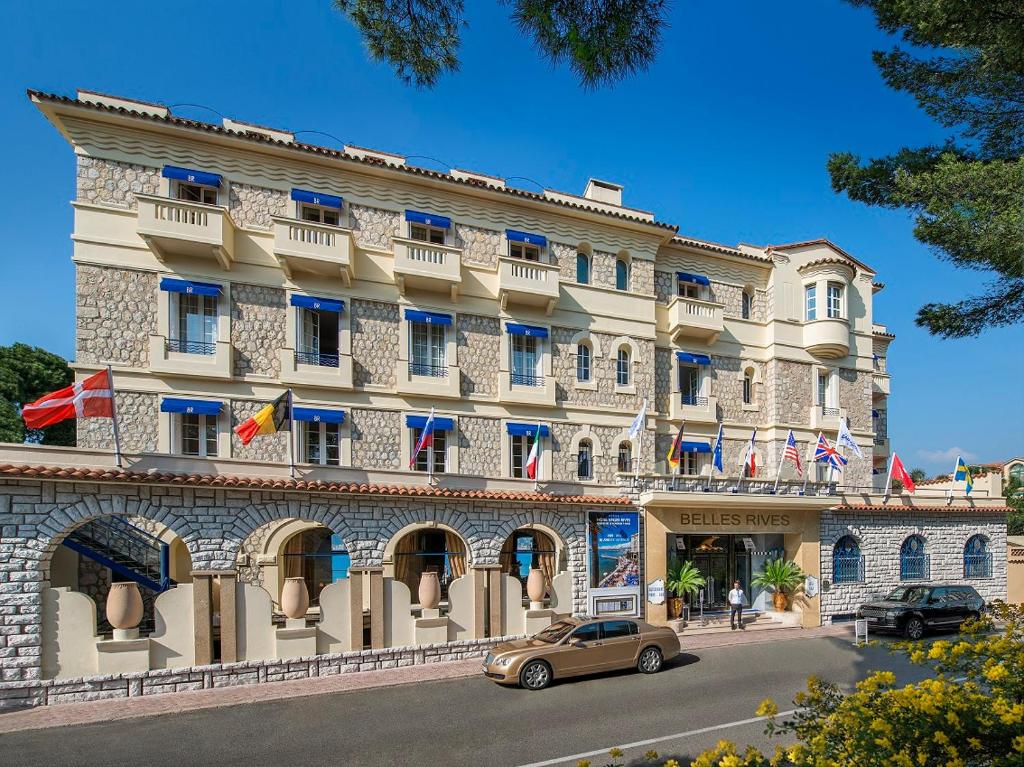 a building with a car parked in front of it at Hôtel Belles Rives in Juan-les-Pins