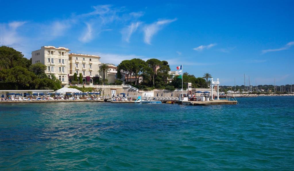 a dock in the water next to a large building at Hôtel Belles Rives in Juan-les-Pins