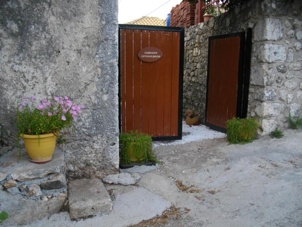 una entrada a una casa con una puerta de madera y flores en Carsazzio Cottage House en Kariá