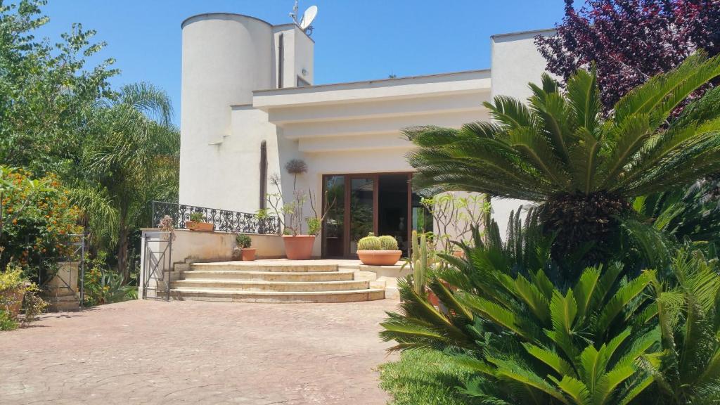 una casa blanca con algunas plantas delante de ella en B & B Villa Flora en Mondello