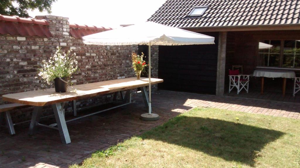
a wooden bench sitting under an umbrella on a patio at Dijkwoning Cadzand in Cadzand
