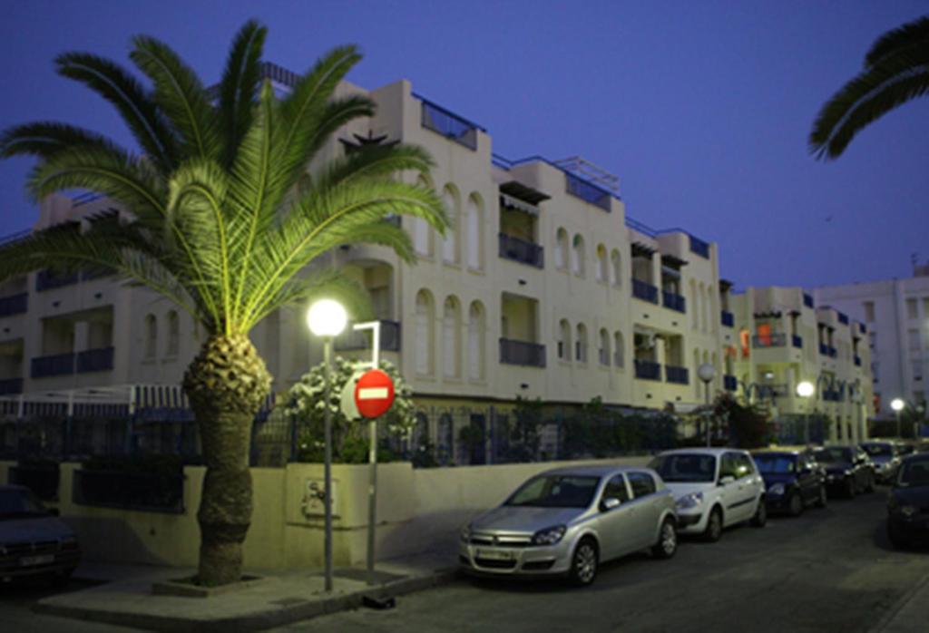 a palm tree and cars parked in front of a building at Azucena in Garrucha