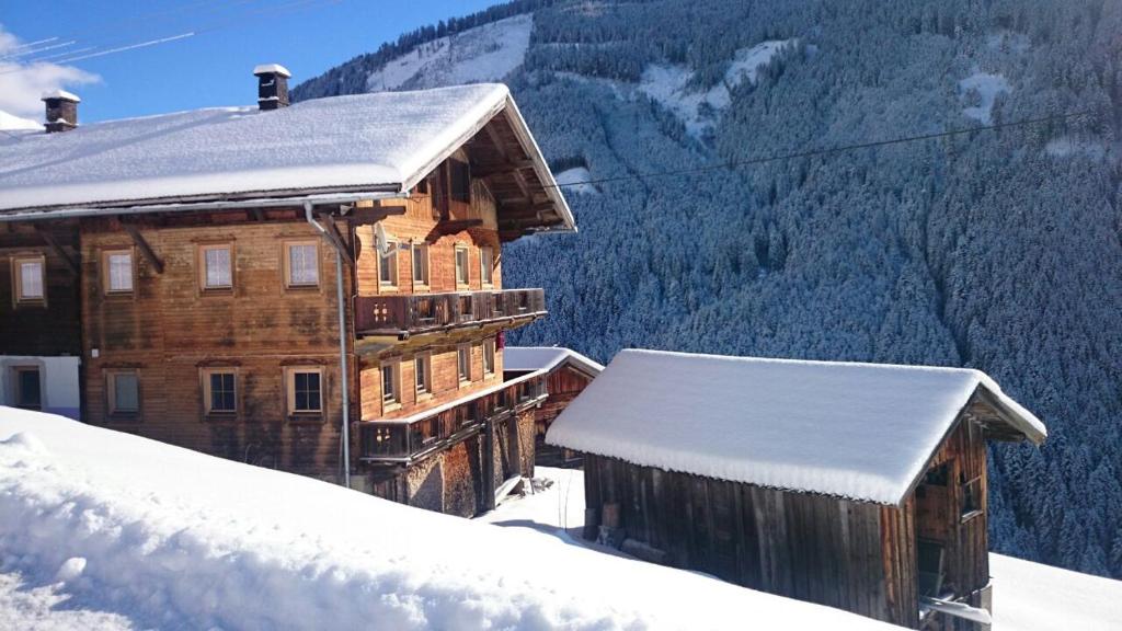 a wooden building covered in snow with mountains in the background at Steinwandhütte in Stummerberg