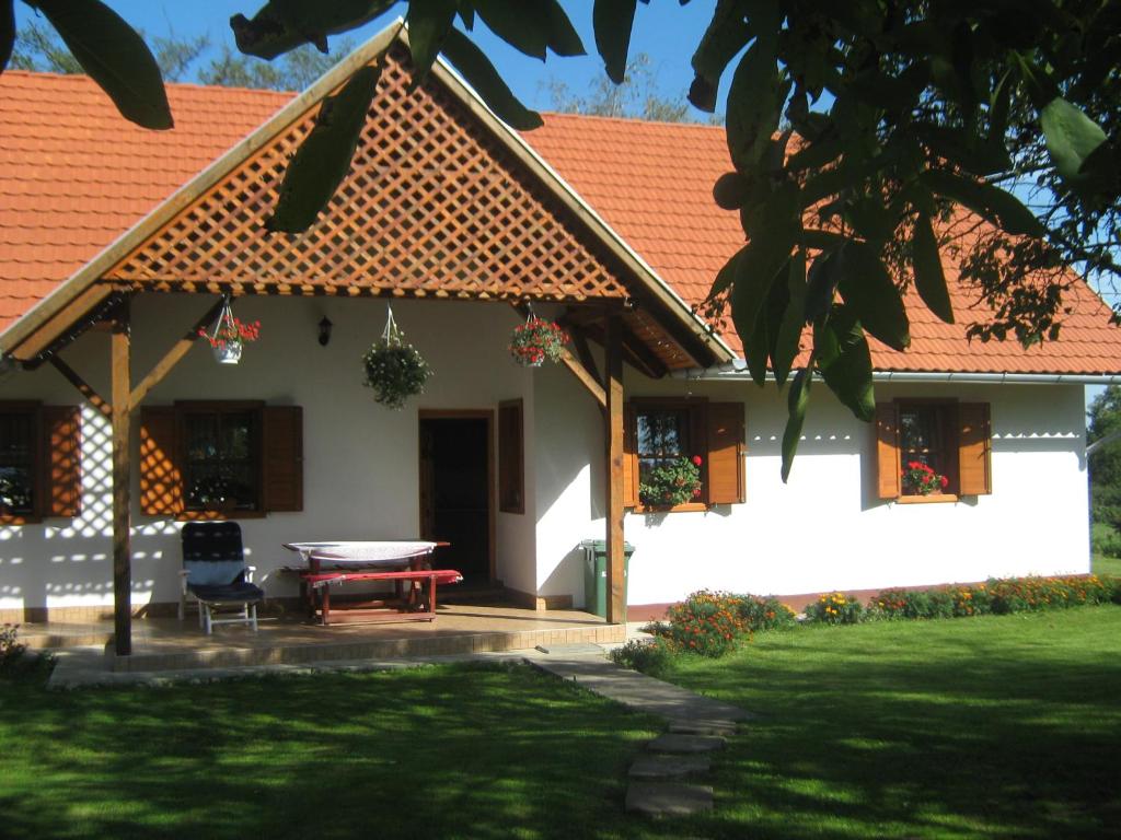 a white house with an orange roof and a table at Vendégmarasztaló Porta in Szalafő