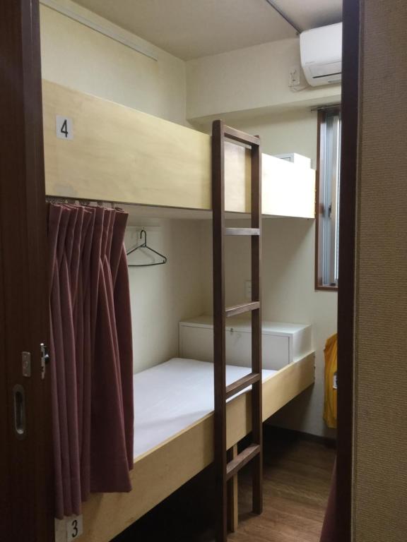 a room with a bunk bed with a ladder at Yamate Rest House (Male Only) in Tokyo