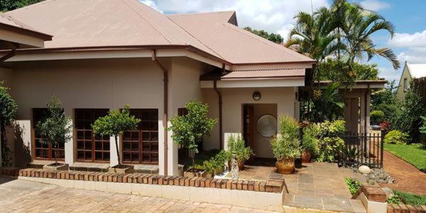 a house with a porch with trees in front of it at 93 on Celliers Guesthouse in Louis Trichardt