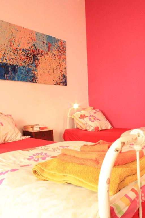 een slaapkamer met 2 bedden en roze muren bij Pássaro do Fogo in Trafaria