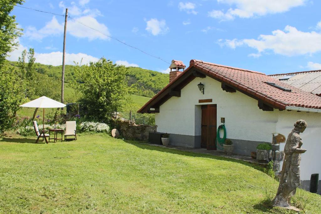 una pequeña casa blanca con mesa y sombrilla en Lazkotzenea en Mezkiriz