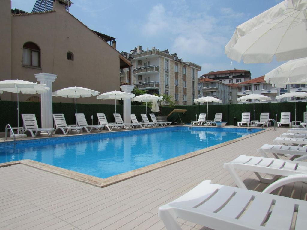 una piscina con sillas y sombrillas blancas en Koc Hotel, en Karasu