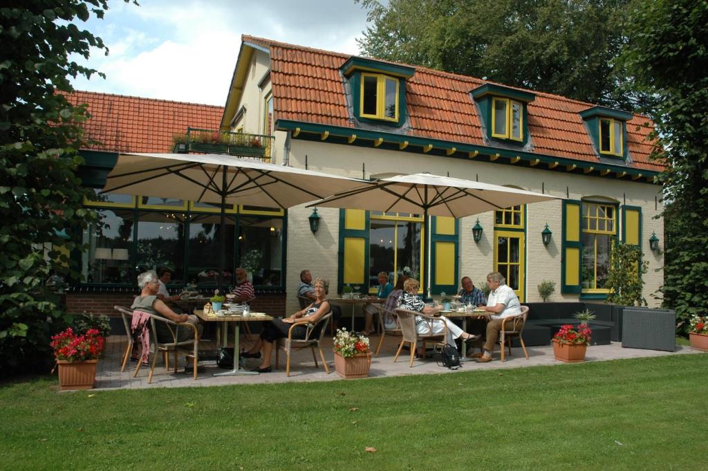 un groupe de personnes assis à des tables à l'extérieur d'un bâtiment dans l'établissement Hotel Vierhouten, à Vierhouten