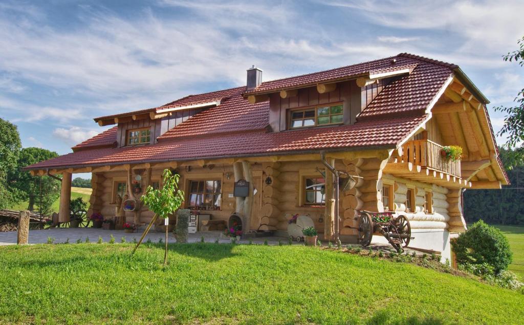 une grande maison en bois avec un toit rouge dans l'établissement Holzhaus Lugerhof, à Roding