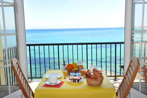 a table on a balcony with a view of the ocean at Hôtel de la Plage Les Arcades in Algajola