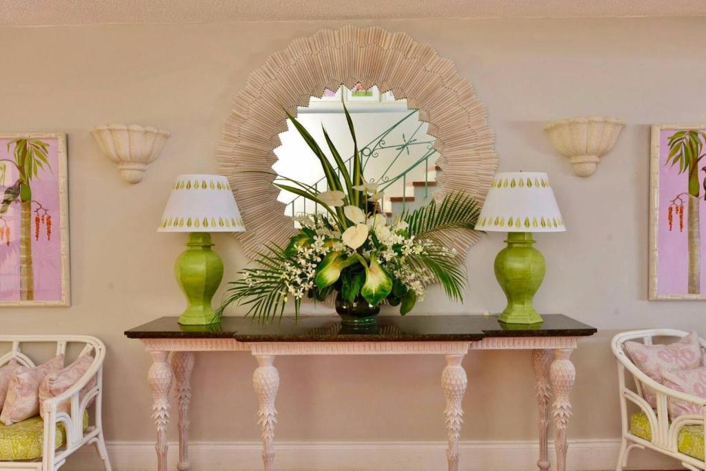 a table with a mirror and a vase of flowers at Cobblers Cove - Barbados in Saint Peter
