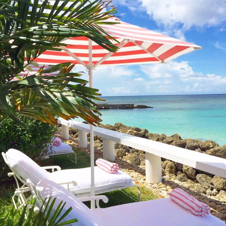 a beach with chairs and an umbrella and the ocean at Cobblers Cove - Barbados in Saint Peter