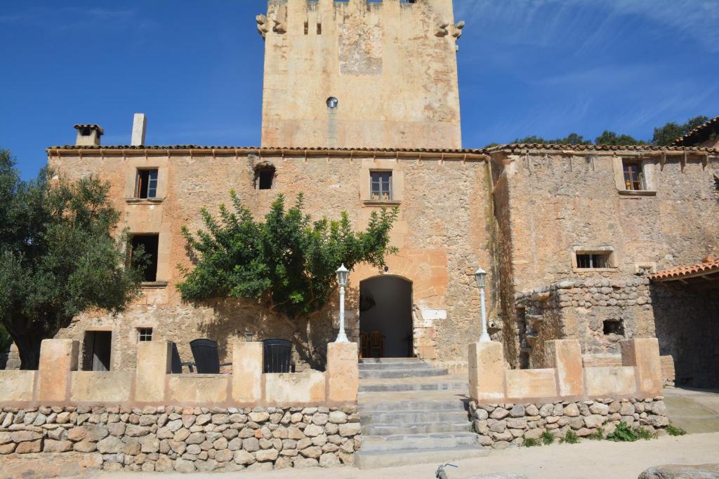 - un bâtiment en pierre avec une tour et une porte dans l'établissement Finca Sa Duaia de Dalt, à Artà