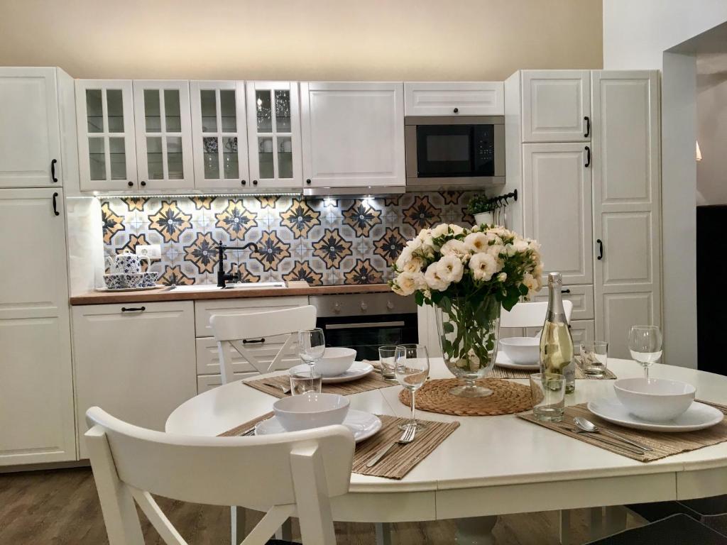 a white kitchen with a table with a vase of flowers at Julija & Filip Apartments in Ljubljana
